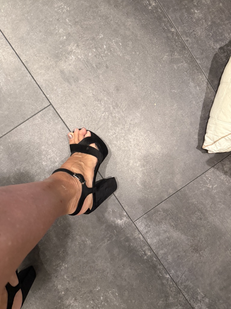 Leg in black high heel on tile floor